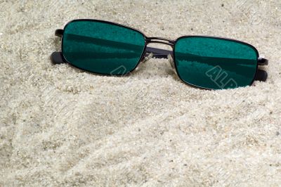 blue sunglasses lost in beach sand