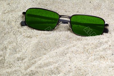 green sunglasses lost in beach sand