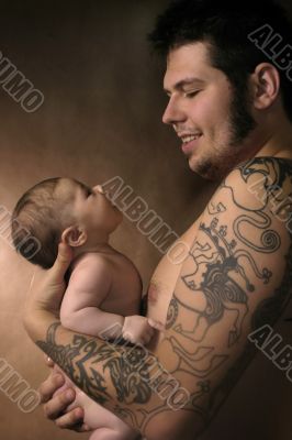 The baby on hands at the man with a tattoo