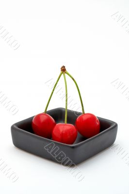 Three cherries in a black bowl