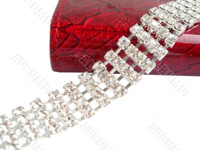 Close up of dimond necklace with beautiful red purse on white
