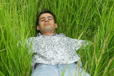 Boy relaxing in high green grass