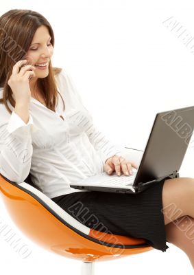businesswoman with laptop and phone in orange chair