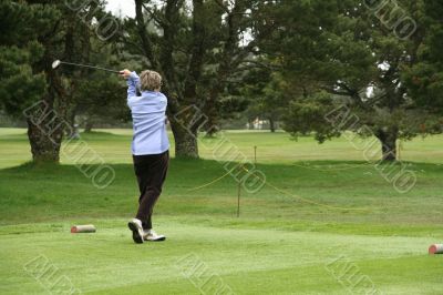 Woman golfer teeing off