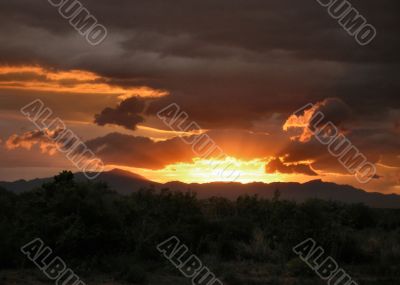 Fiery Sun setting into Rain Clouds