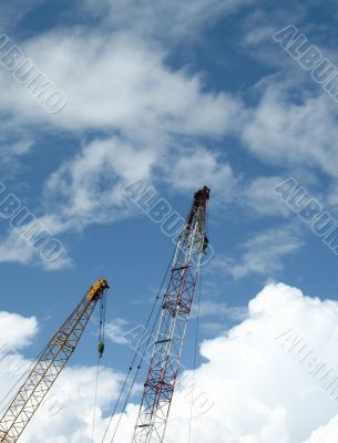 Double construction cranes against blue sky