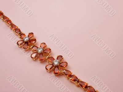 Jewelry bracelet with garnets on pink background