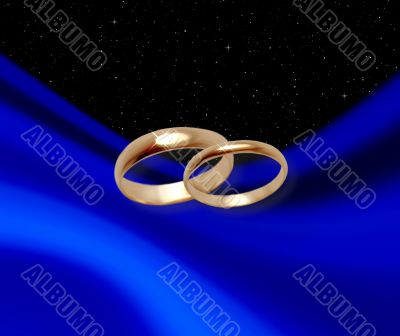 Wedding rings on dark blue drapery