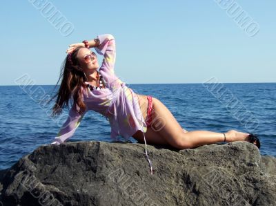The sexual girl lays on a rock