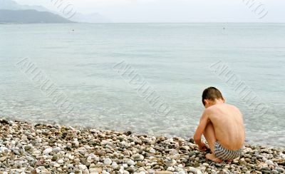 Boy, sea and pebble