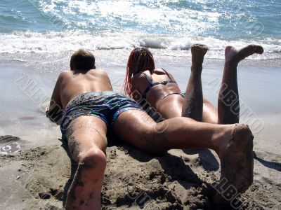 couple lying on the seashore warm, sunny day