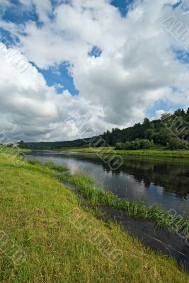 deep blue waters of the river, green grass and blue sky