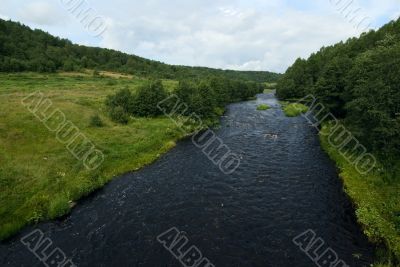 deep blue waters of the river, green grass and blue sky