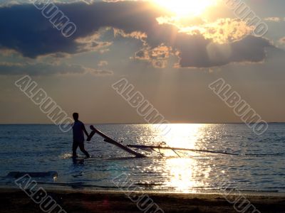 The guy drags the windsurf on a sunset