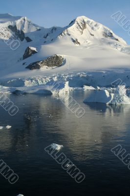 Glaciated mountain, reflected in ocean mirror,