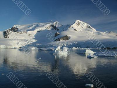 Glaciated mountain, reflected in ocean mirror,