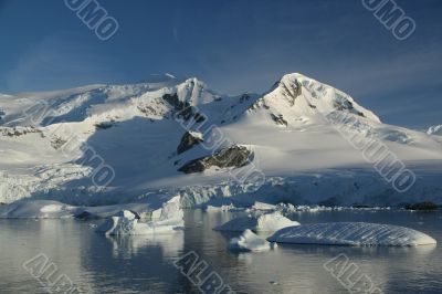 Glaciated mountain, reflected in ocean mirror,