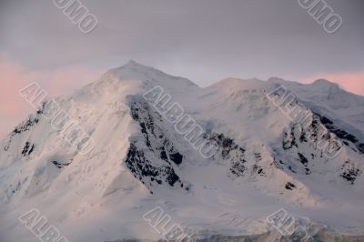 Subtle alpenglow lights snowy mountain