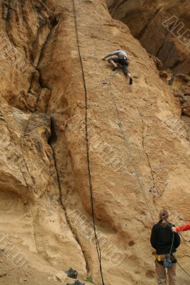 Woman belaying a climber on rock face