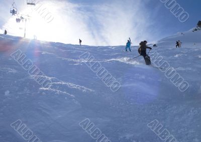 Backlit skiers in powder snow