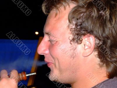 The guy smokes a hookah and smiles