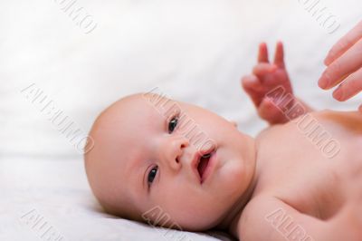 Mother massage baby. Baby look at camera