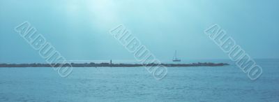 Sea landscape with a breakwater and a yacht