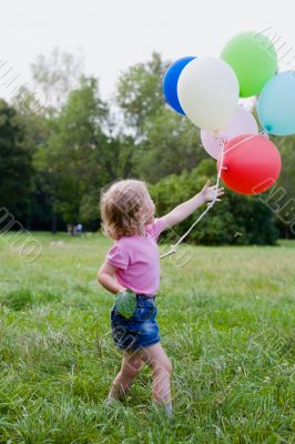 girl with balloon runs on lawn