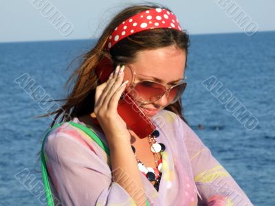 The beautiful girl talks by a mobile phone