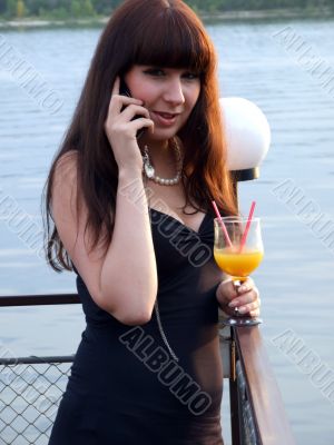 The girl in hands talks to a cocktail by a phone