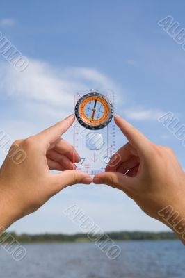 hand with compass on background sky