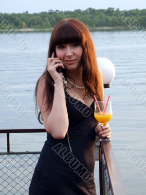The girl with a cocktail speaks to mobile phone