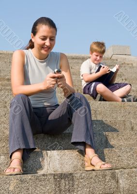 girl with mobile. boy reads book