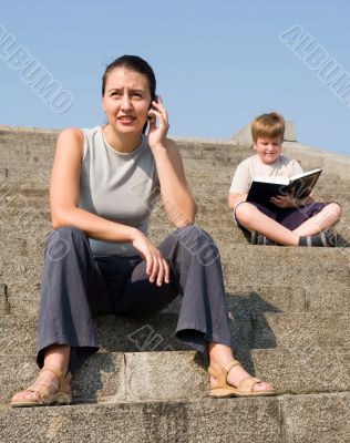 girl with mobile. boy reads book