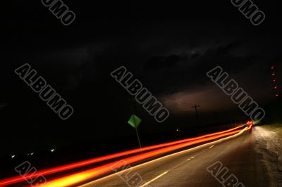 Cars streaking by funnel cloud on horizon