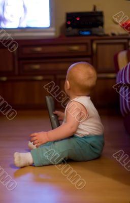 Cute little boy hold remote control and watching TV at home