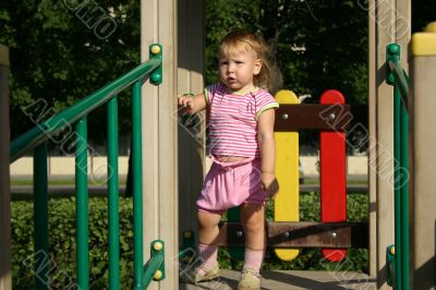 Babygirl in sunset lights on playground