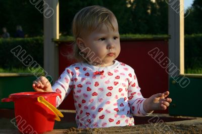 Little girl in sandbox looking away