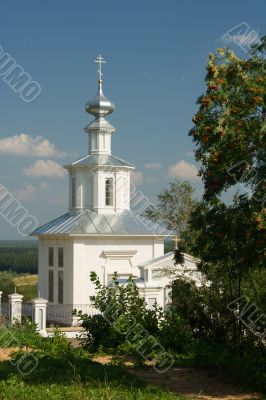 White Christian church on a background of a tree