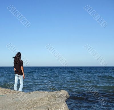 Girl on Rock Looks out to Water