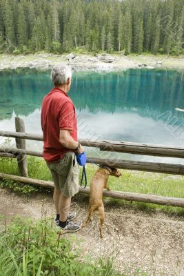 man and dog by blue lake