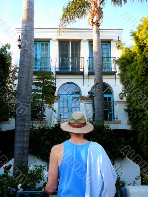 Man In Hat Looking At Tropical Home