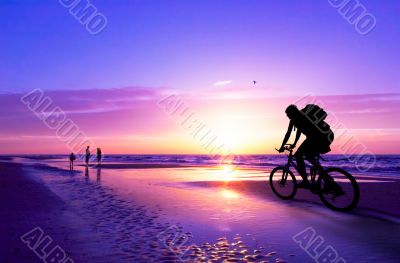 mountain biker on beach and sunset