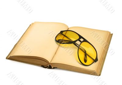 open book with yellow sunglasses on white
