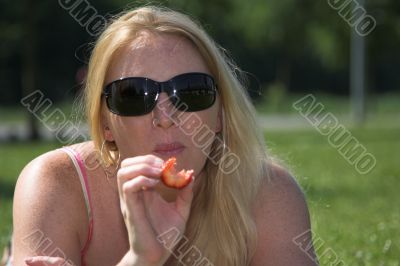Blond woman eating a strawberry