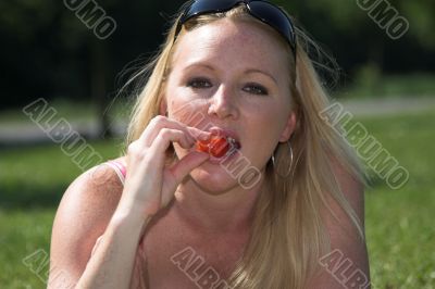 Blond woman eating a strawberry