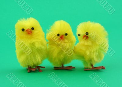 three toy chickens on green background