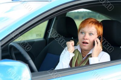 Red-haired woman with mobile-phone in a car
