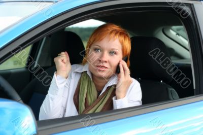 Red-haired woman with mobile-phone in a car