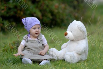 baby on the grass with a bear toy